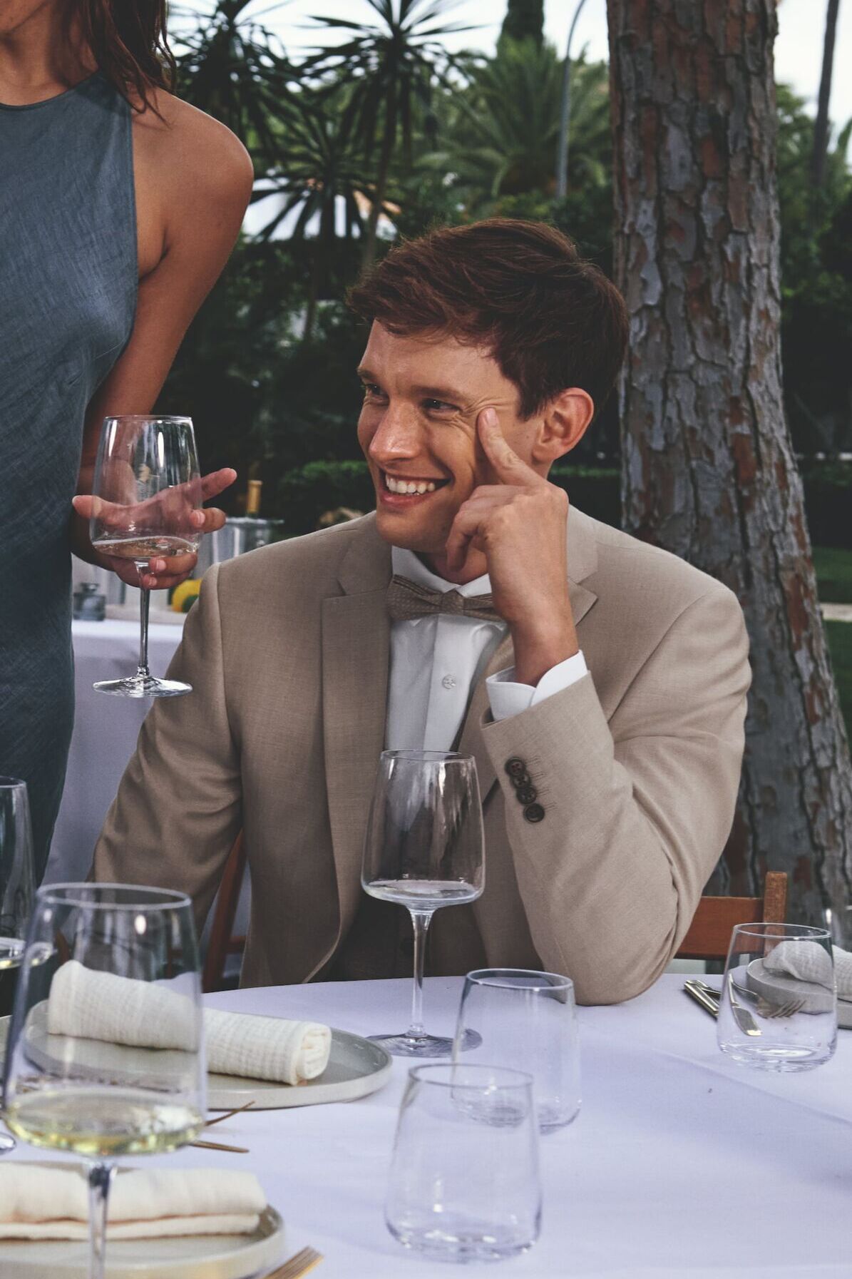 Männliches Modell in schicken hellbraunen Anzug von Roy Robson sitzt an einem gedeckten Tisch