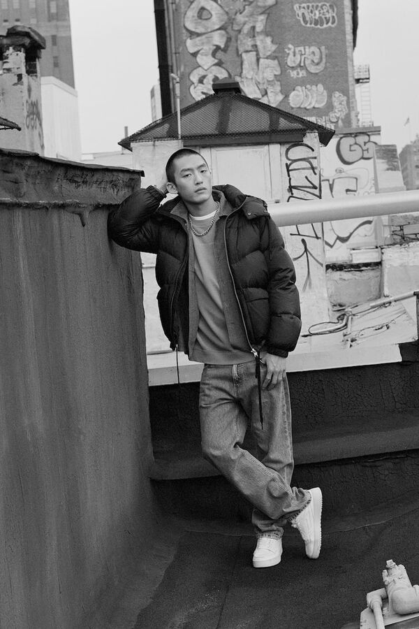 Schwarzweiß-Foto eines männlichen Models in Baggy-Jeans, Pullover und Puffer-Jacket von Marc O Polo Denim