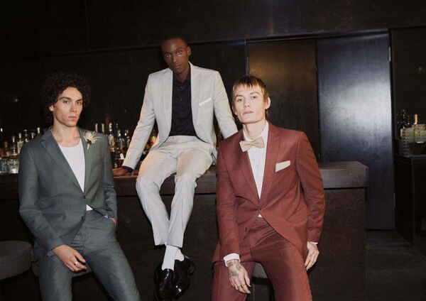 3 männliche Models in verschiedenen Anzügen von CG-Club of Gents posieren an einer Theke