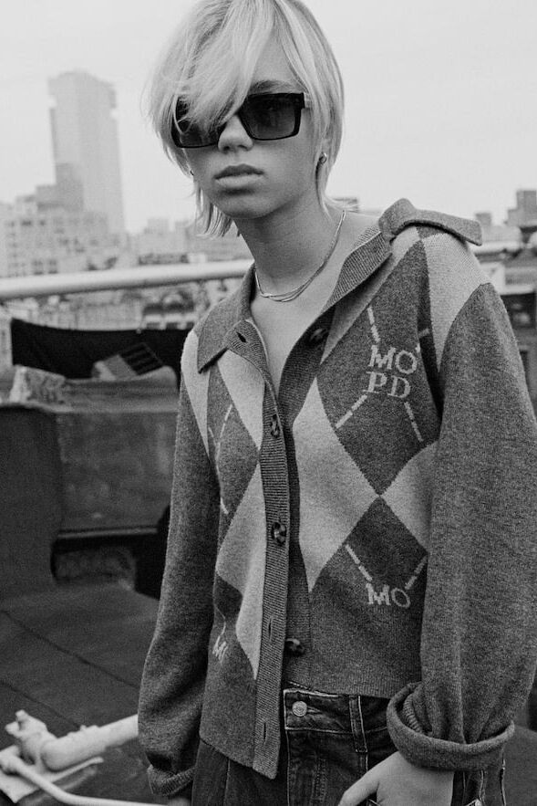 Schwarzweiß-Foto eines weiblichen Models in einer gemusterten Strickjacke von Marc O Polo Denim posiert auf einem Hochhausdach