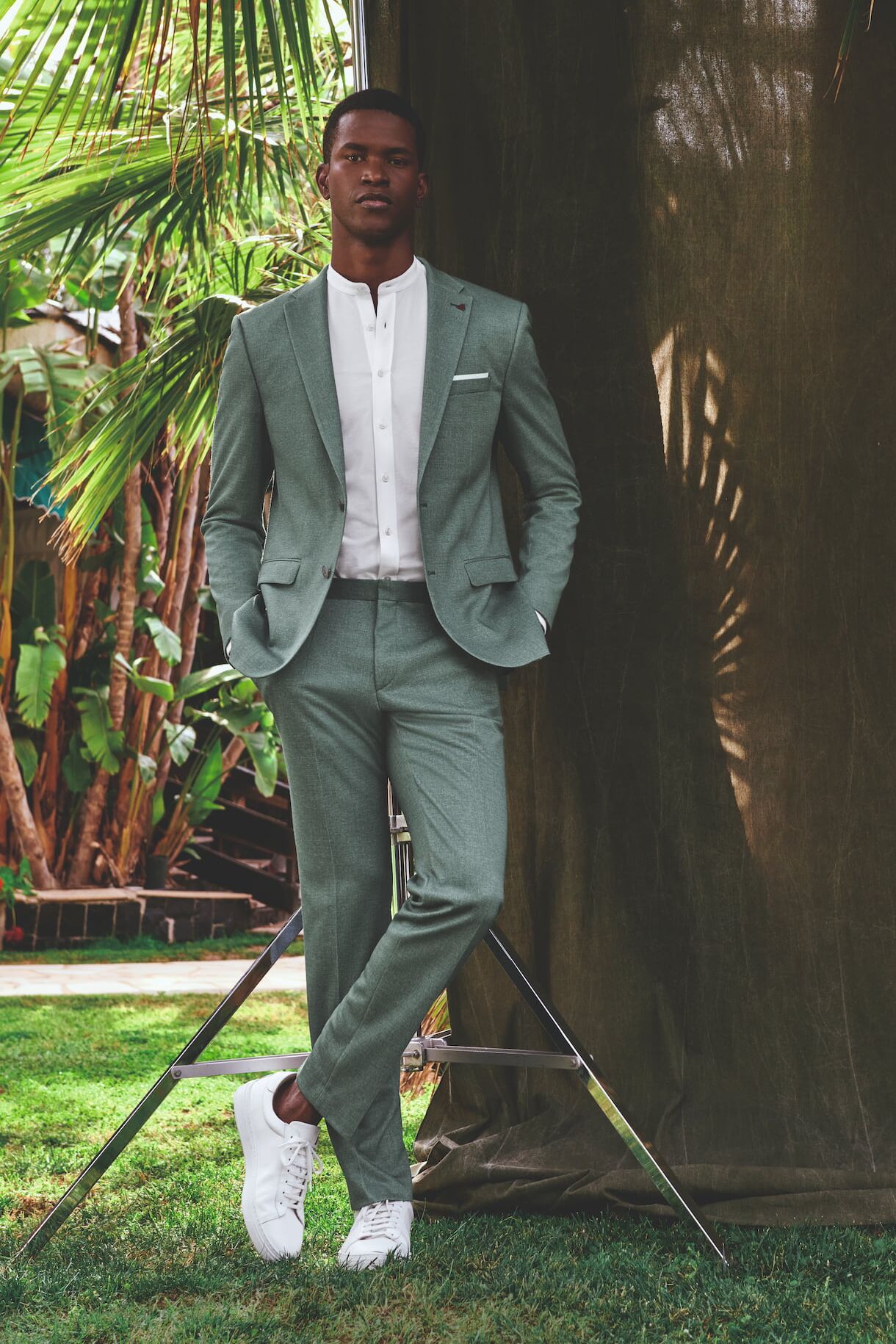 Männliches Modell in schicken grünen Anzug von Roy Robson posiert in einem Garten