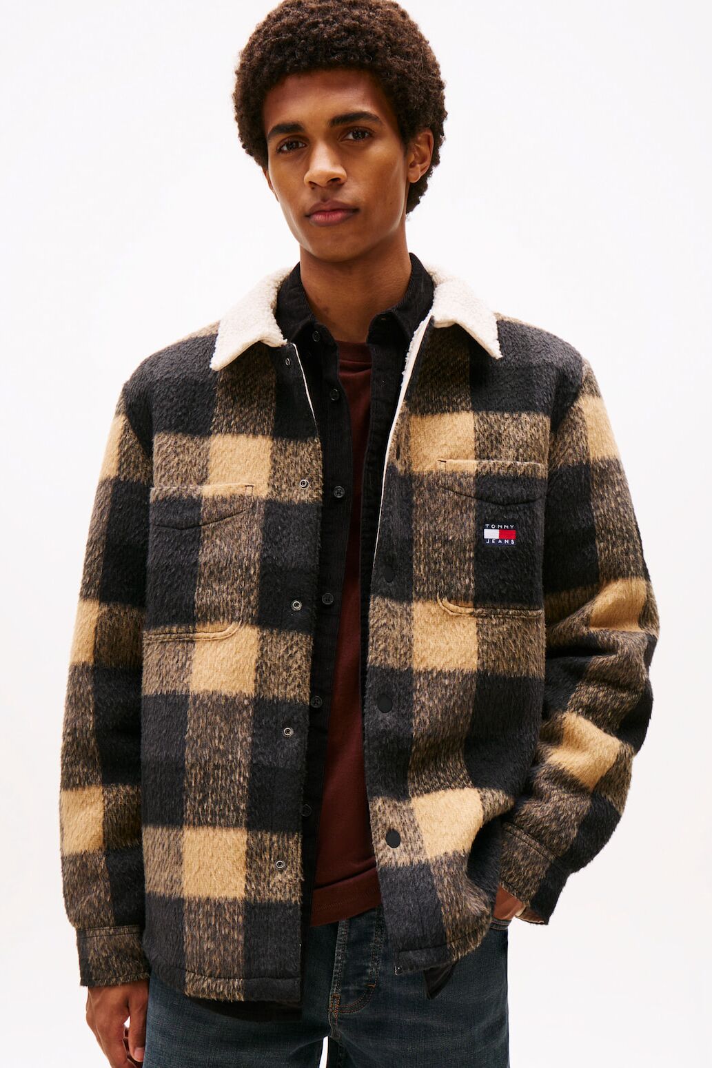 Männliches Modell in schwarz-gelb karierten Overshirt von Tommy Jeans posiert mit einer Hand in der Hosentasche