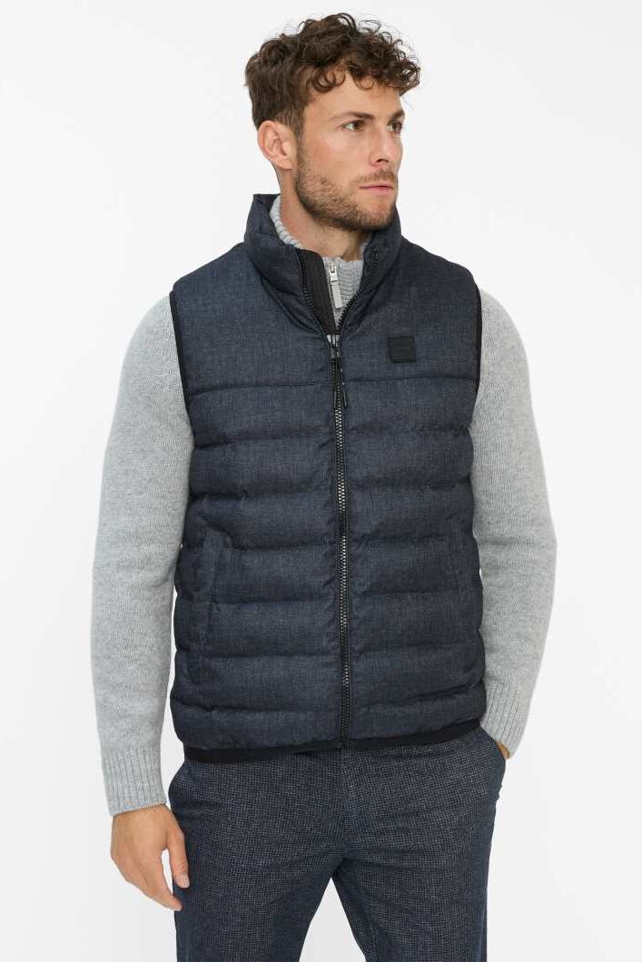 Maennliches Modell in dunkelblauer Steppweste von Brax posiert mit einer Hand in der Hosentasche