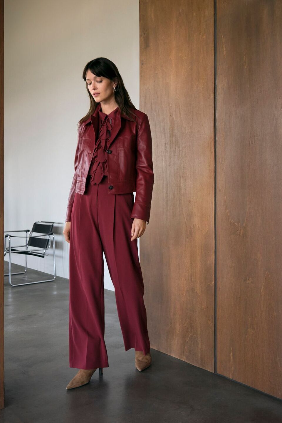 Weibliches Modell in roter Culotte und dunkelroter Bikerjacke von Luisa Cerano läuft aus einem Büro