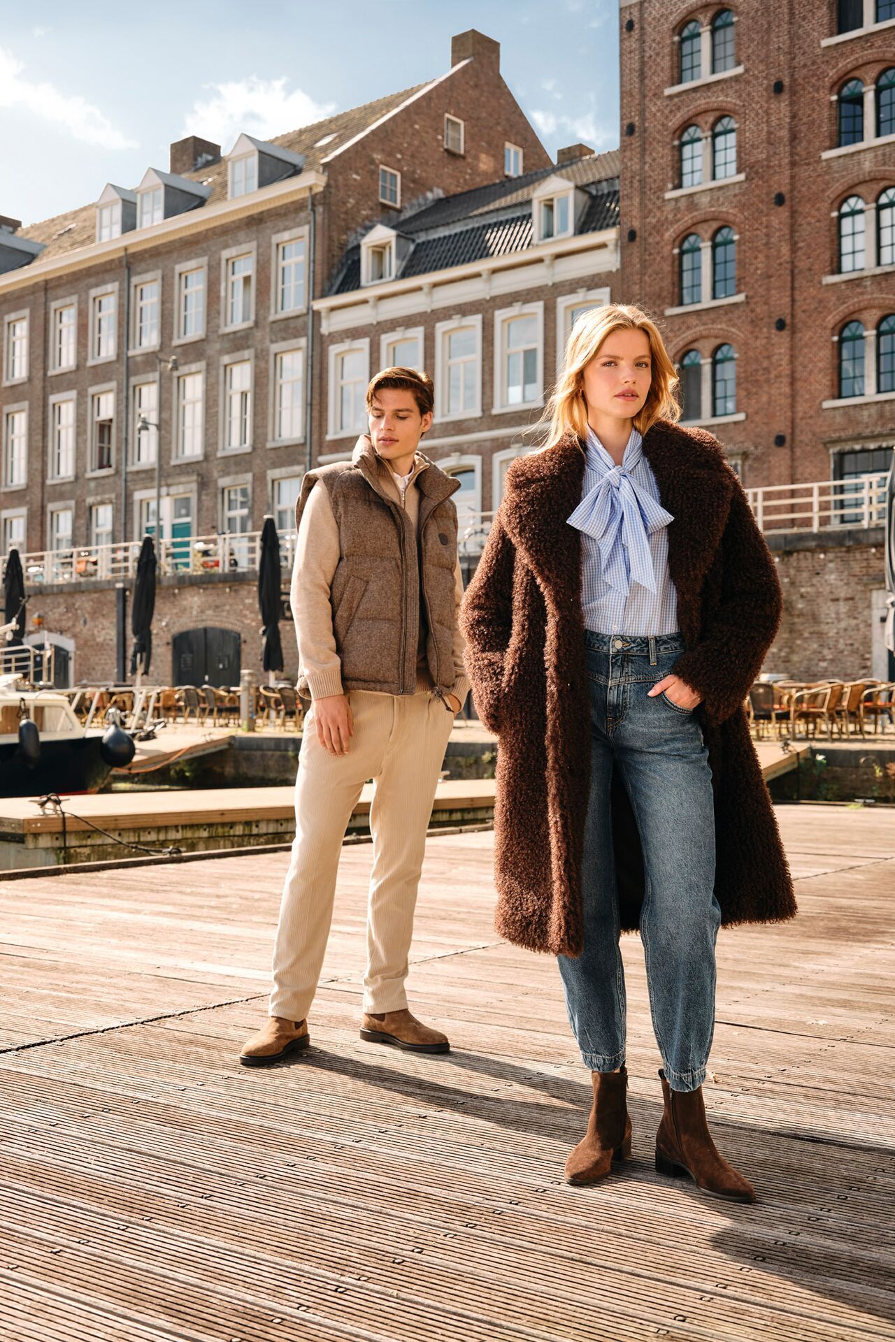 Weibliches und männliches Modell in gesagten Herbst/Winter-Looks posieren gemeinsam auf einem Steg