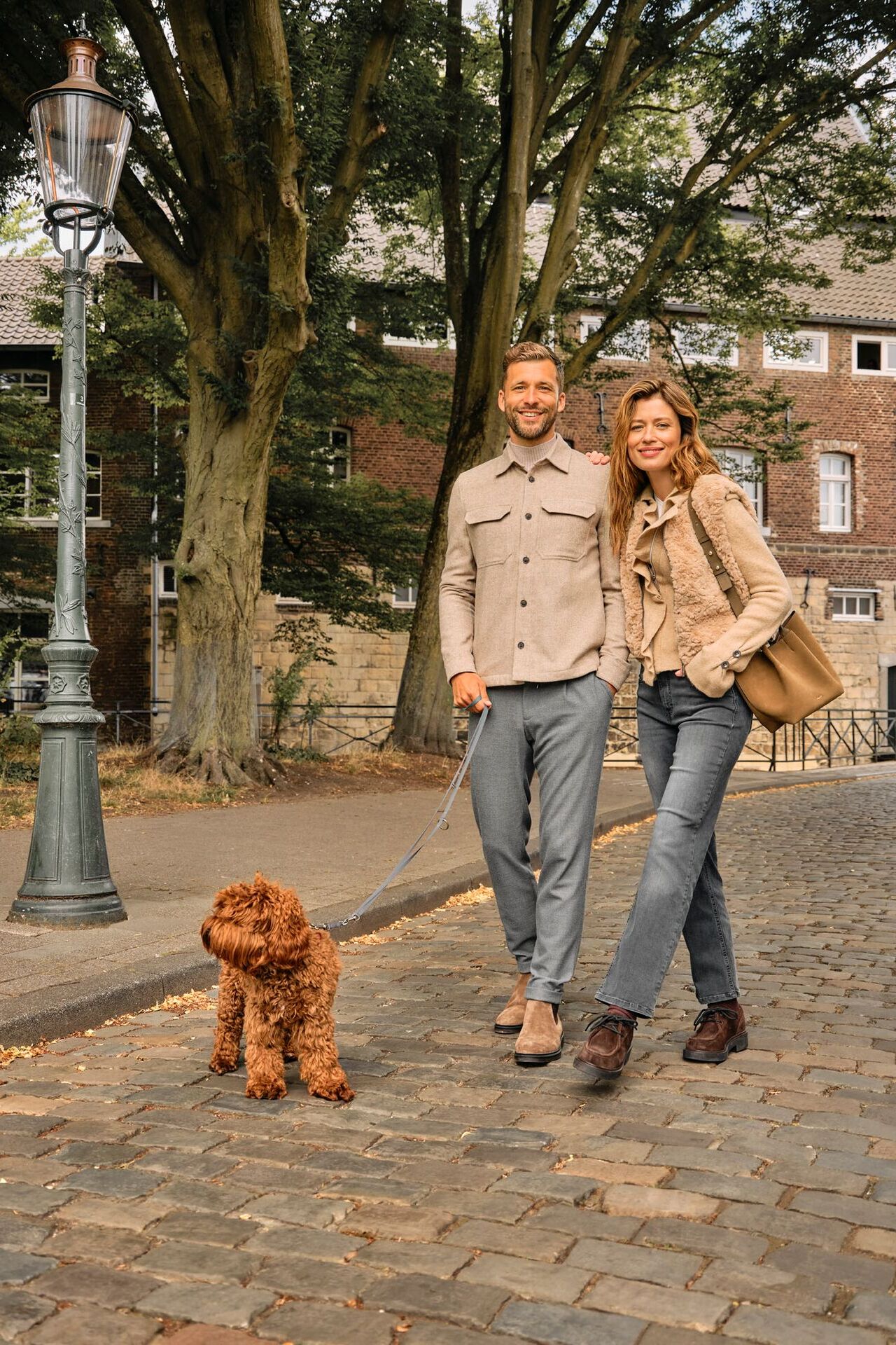 Weibliches und männliches Modell in klassischen Herbst-Looks spazieren mit einem Hund