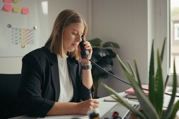Eine Frau sitzt in ihrem Büro und telefoniert.