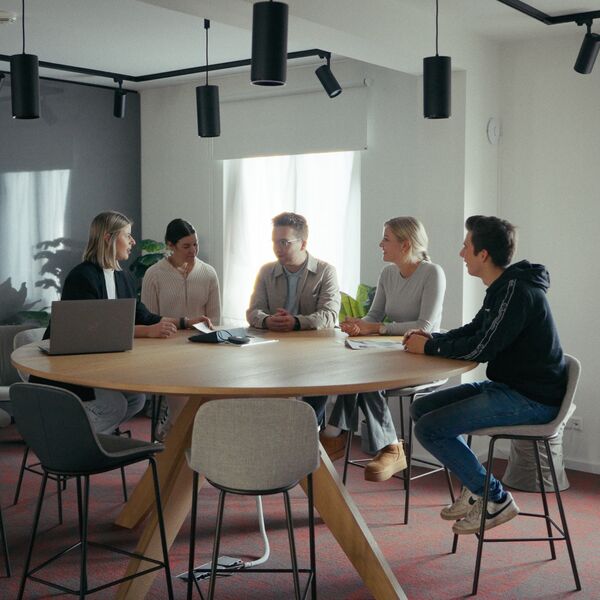 Zinser-Mitarbeiter bei einem Meeting sitzen zusammen an einem runden Tisch.