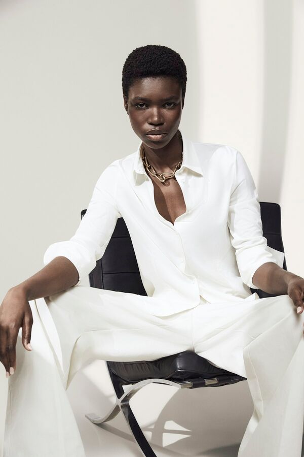 Weibliches Model in weißer Hose und Bluse von BOSS