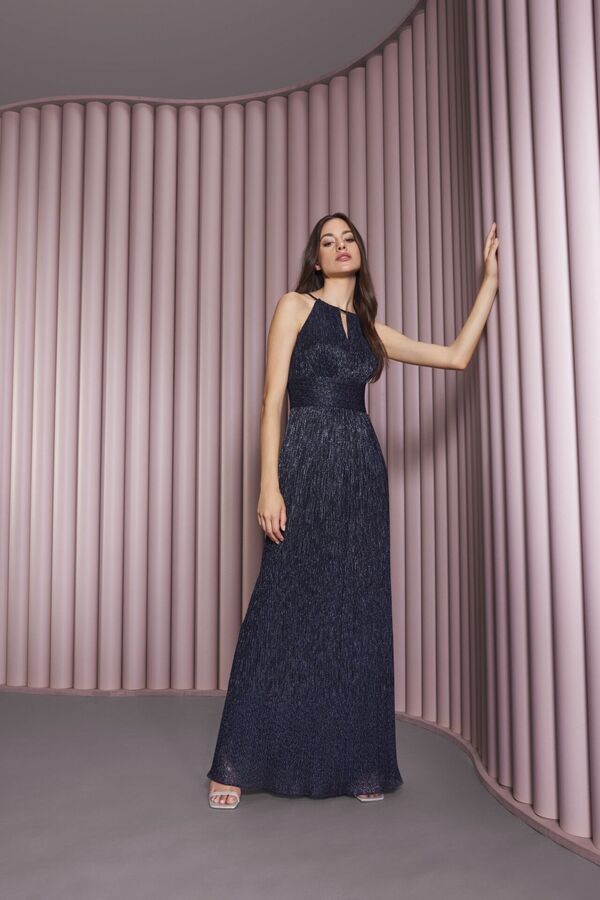 Weibliches Modell in glamourösen schwarzen Maxikleid von SWING stützt sich an einer rosa Wand