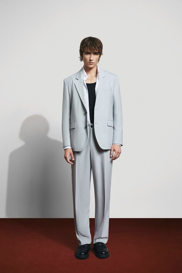 Männliches Modell in hellgrauen Anzug von HUGO RED posiert in einer geraden Haltung