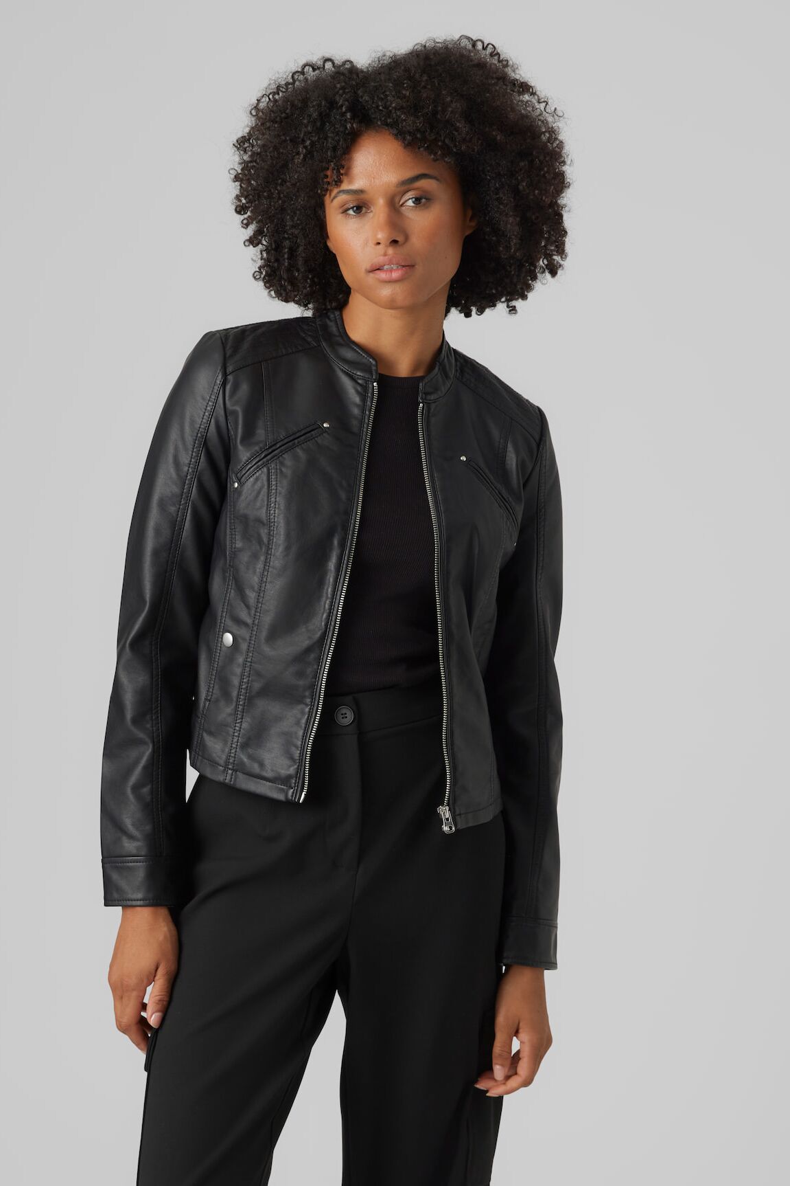 Weibliches Modell in schwarzer Faux Leatherjacke von Vero Moda posiert lässig