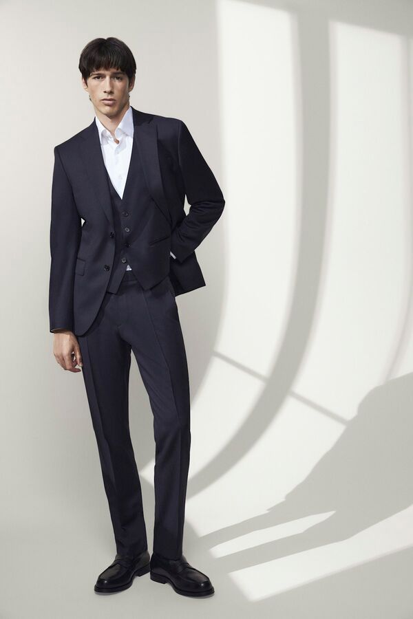 Männliches Modell in dunkelblauen Anzug von BOSS posiert mit einer Hand hinter dem Rücken