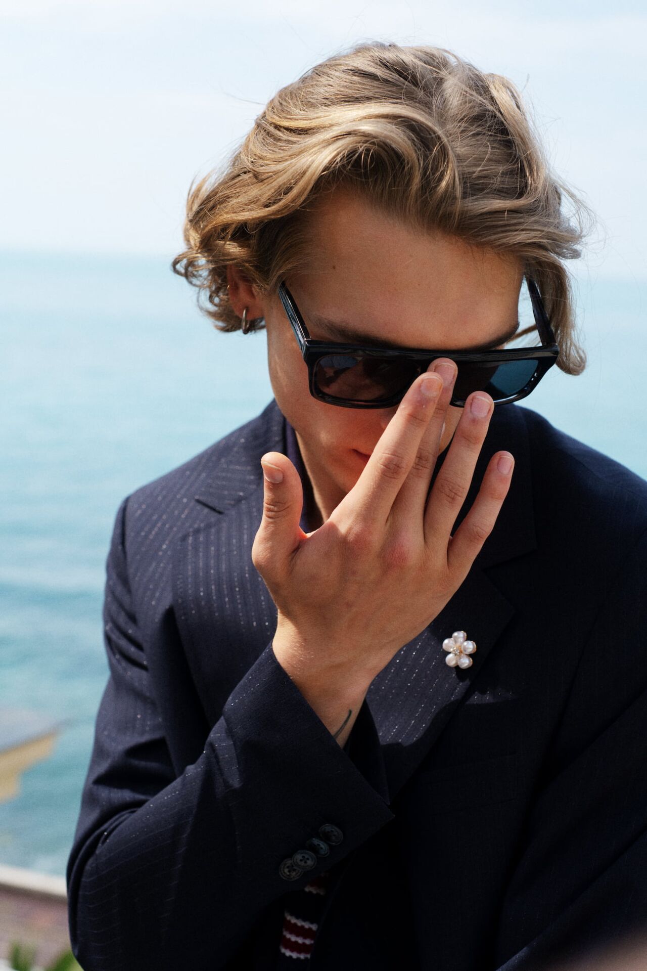 Männliches Model in schickem Anzug von Baldessarini richtet sein Sonnenbrille