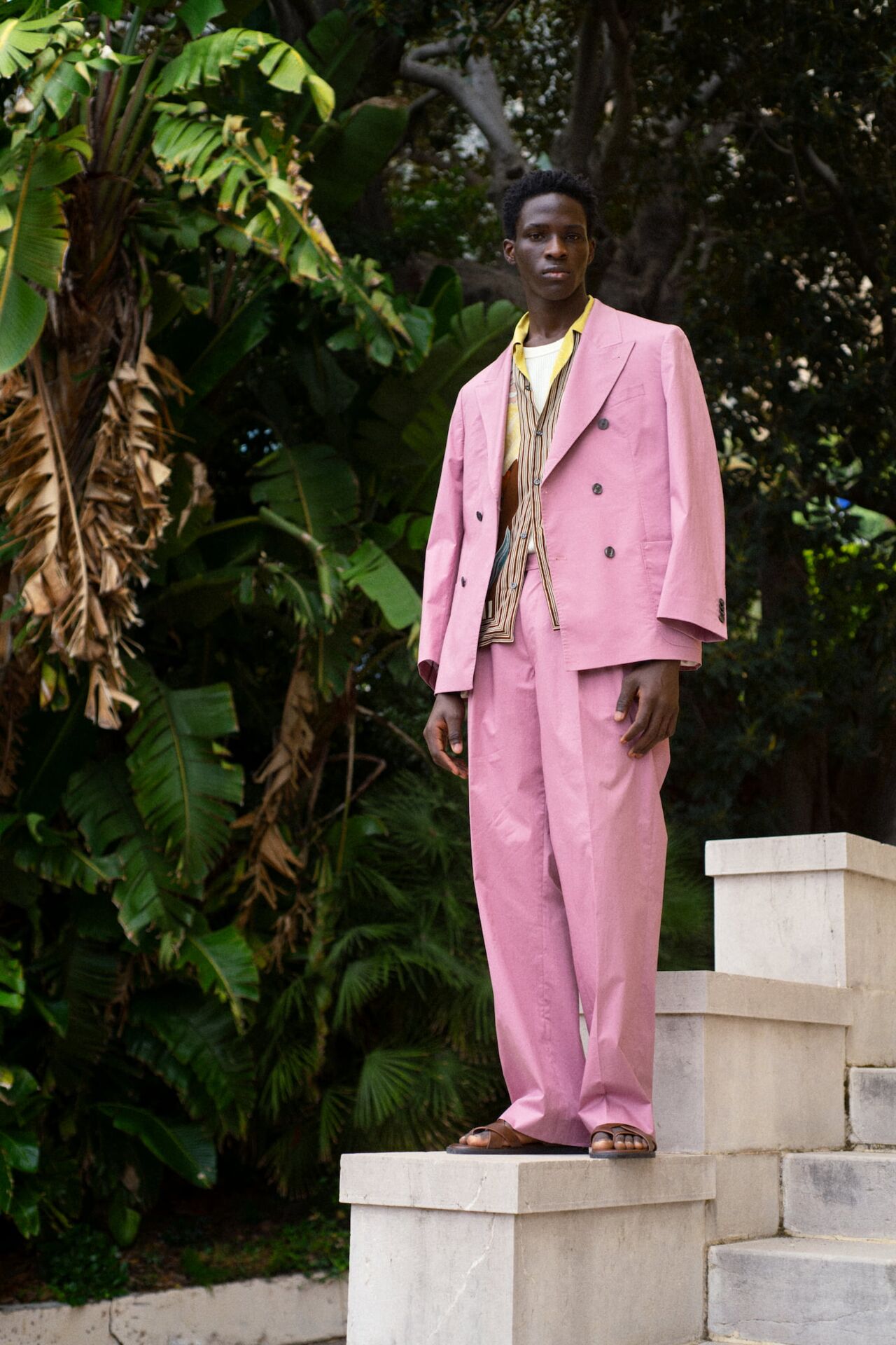 Männliches Modell in einem pinken Anzug von Baldessarini posiert auf einem Stein