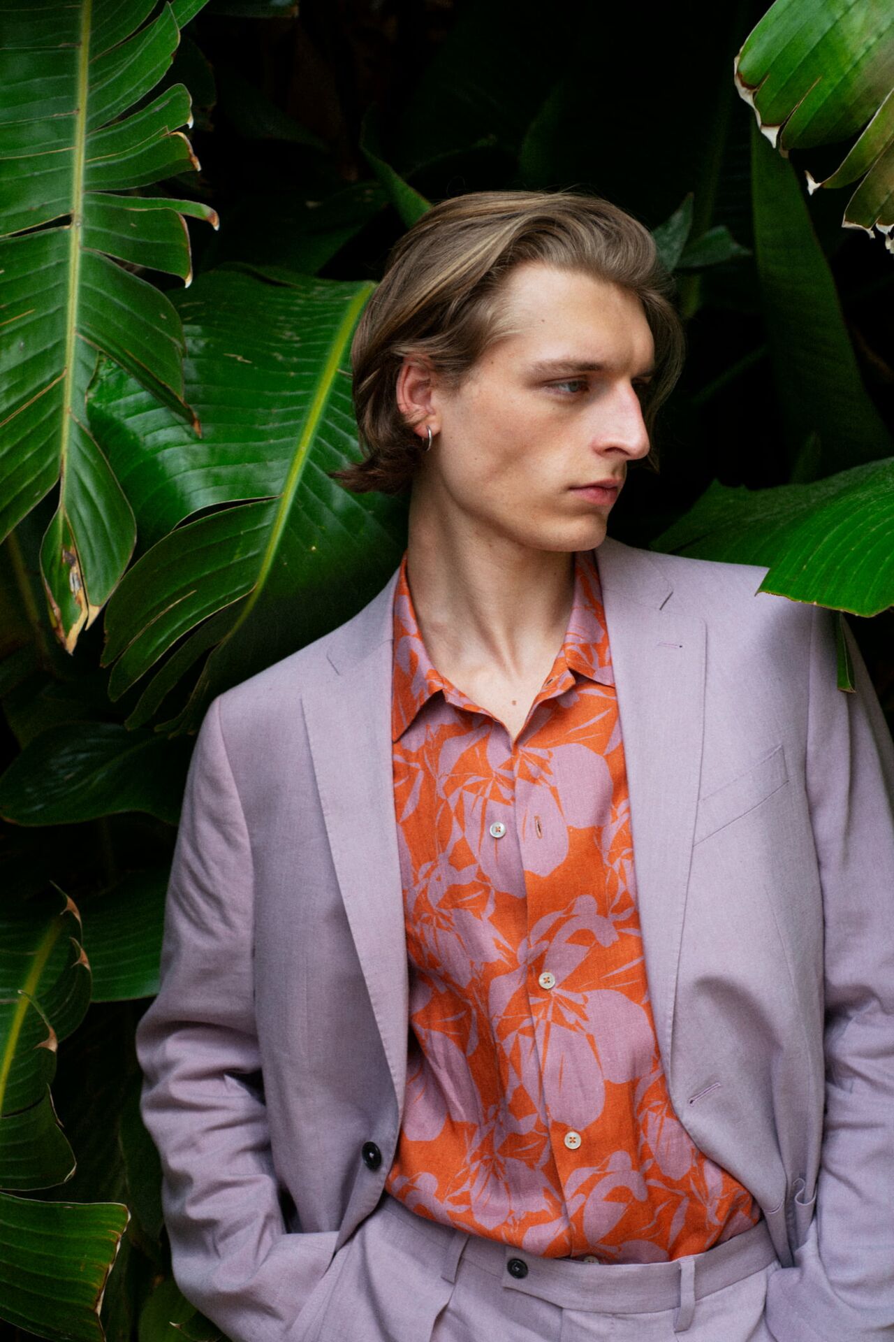 Männliches Modell in orangenen Musterhemd und fliederfarbenen Anzug von Baldessarini posiert lässiger vor großen Pflanzen