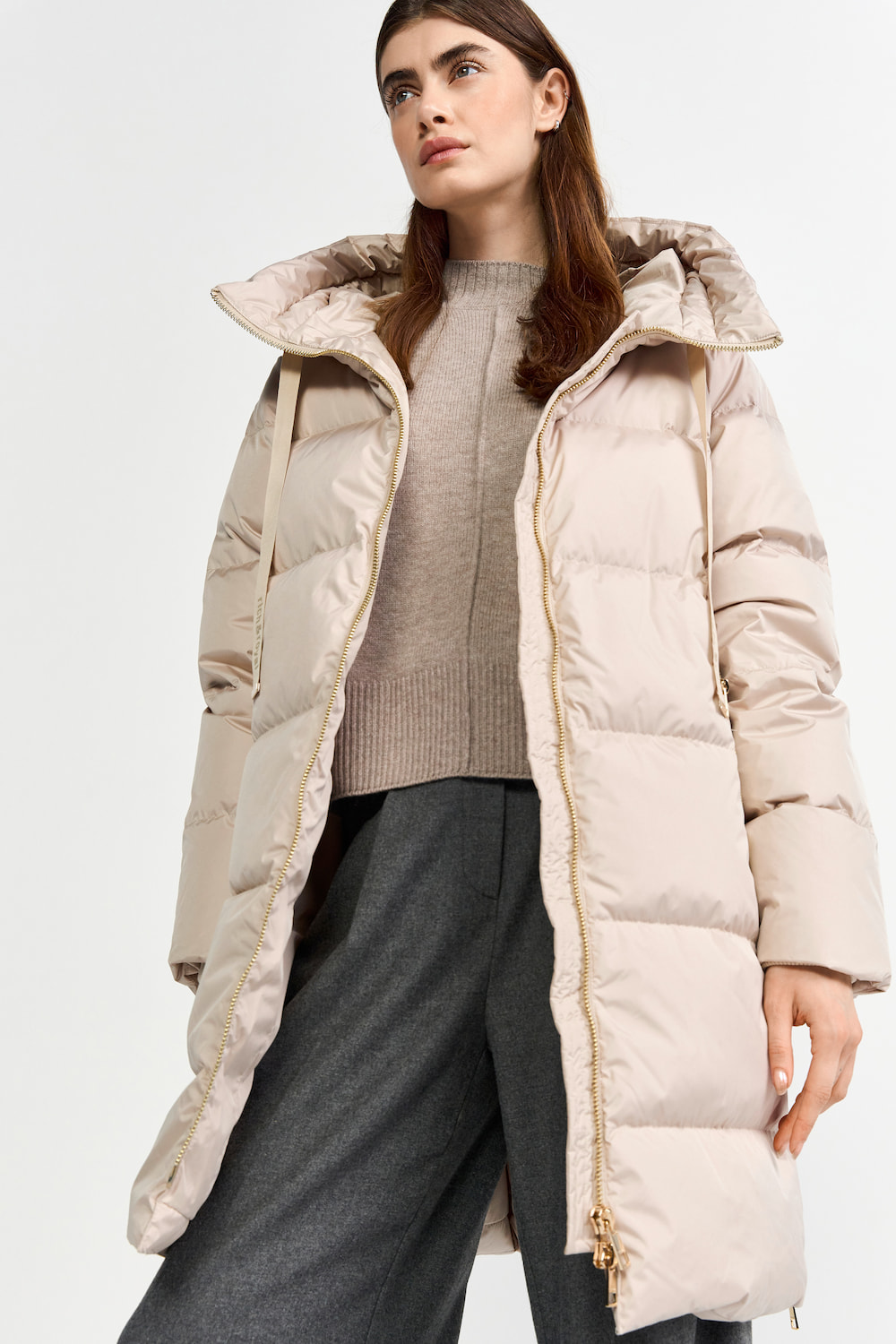 Weibliches Modell in cremeweissen Steppmantel von rich and royal